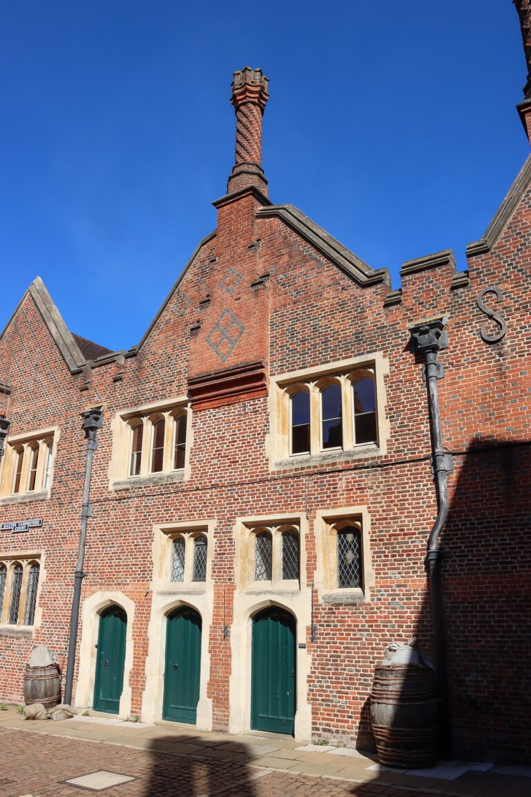 A Tudor gatehouse range of warm brick, chimney and green doors, Hampton Court Palace