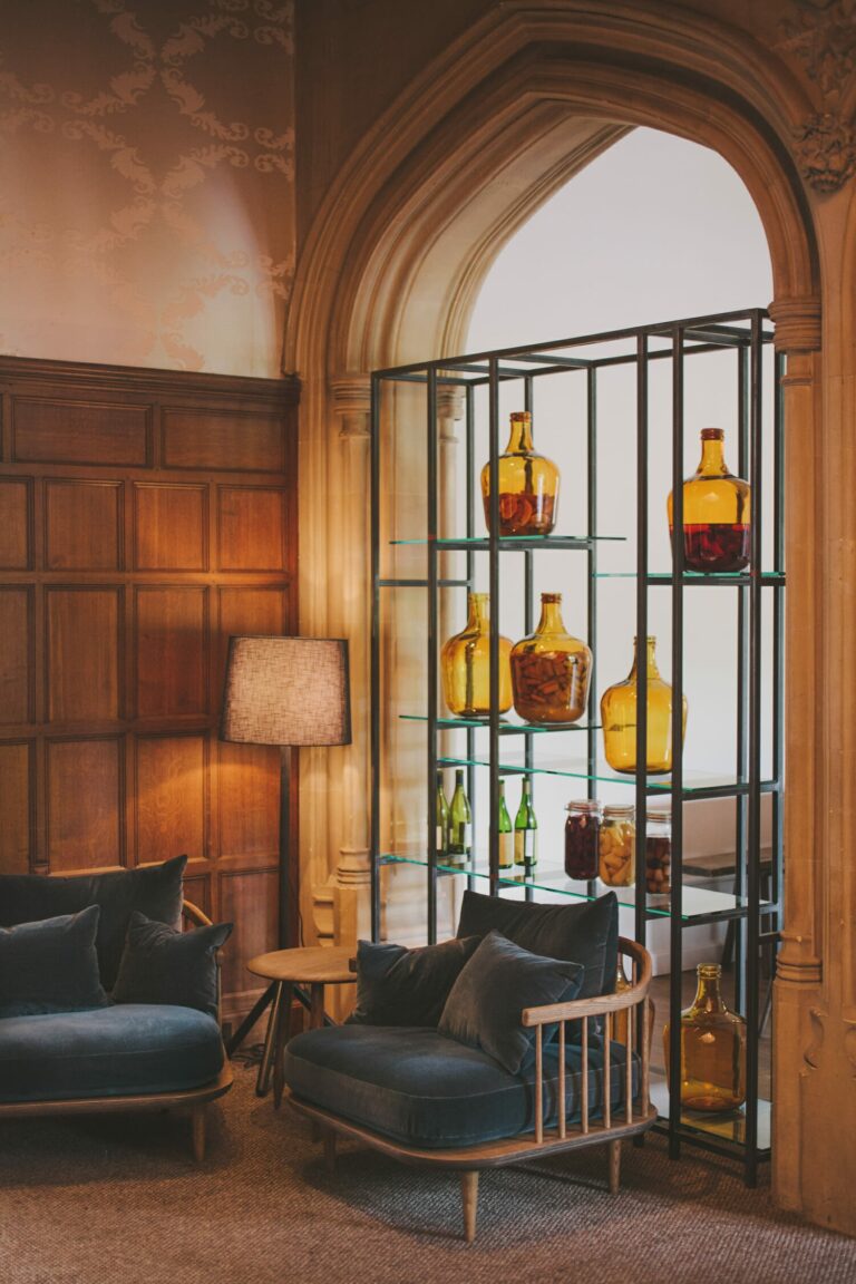 A panelled sitting room with an arched window and shelves of amber glass bottles, Hampton Manor