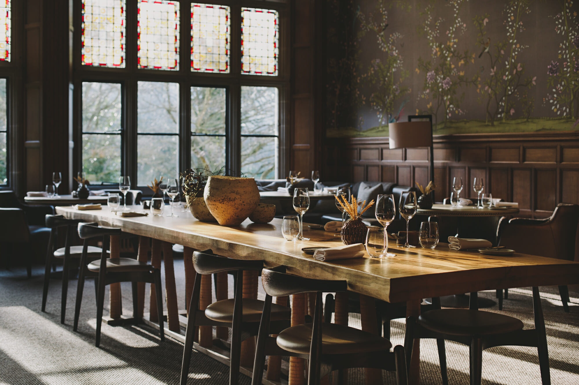 A panelled dining room set at a long wooden table, light through leaded and stained glass, Hampton Manor