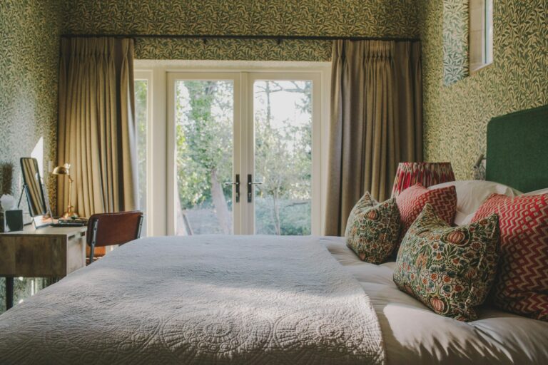 A bedroom with French doors opening to the garden, framed by patterned drapes, Hampton Manor