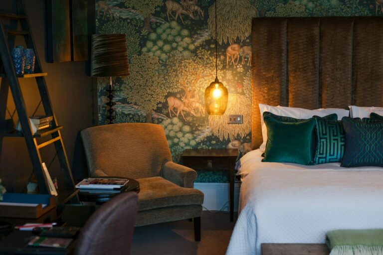 A softly lit bedroom with a velvet armchair and richly patterned walls, Hampton Manor