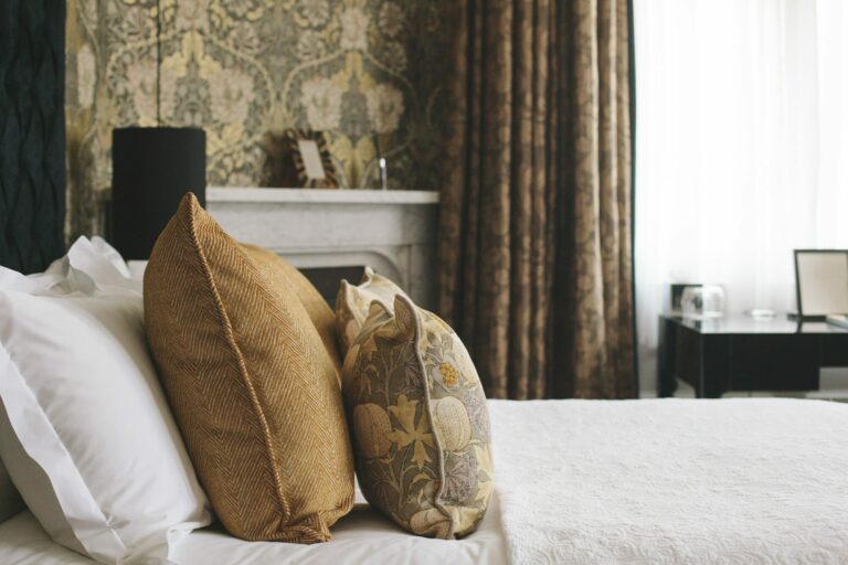A bedroom with a marble fireplace, gold cushions and patterned drapes, Hampton Manor