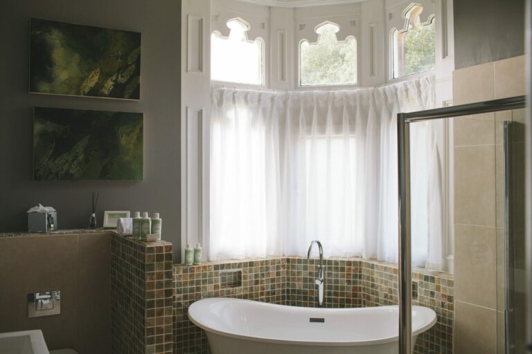 A bathroom with a freestanding tub set into a bay window looking to green, Hampton Manor