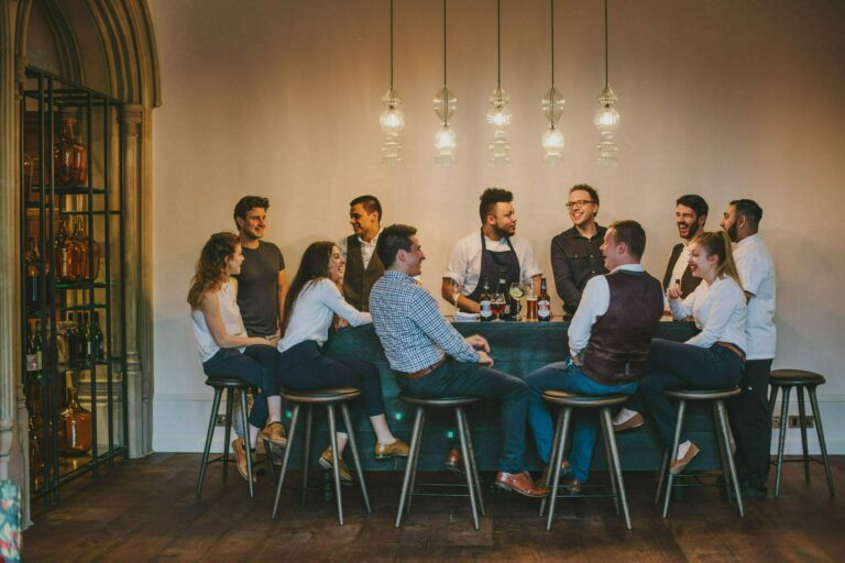 Guests gathered around a bar beneath a row of glowing pendant lights, Hampton Manor