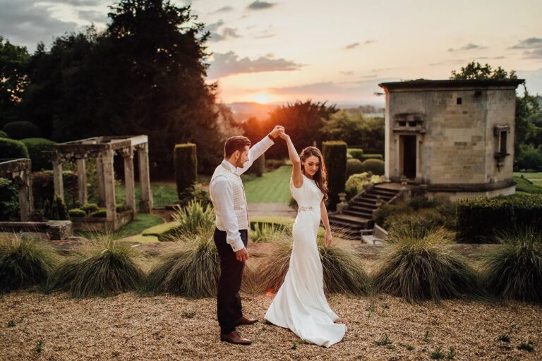 A couple dancing on the gravel in the gardens at sunset, beside a stone pavilion, Harlaxton Manor