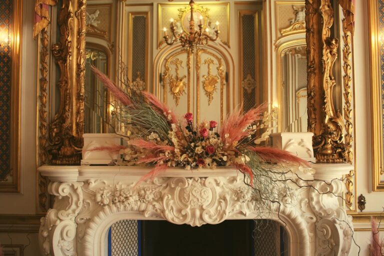 A dried-flower and pampas arrangement on the carved marble fireplace of the Gold Room, Harlaxton Manor