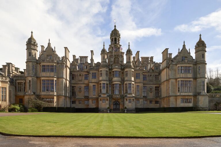 The full entrance front with its central clock tower and turrets, across the forecourt lawn, Harlaxton Manor