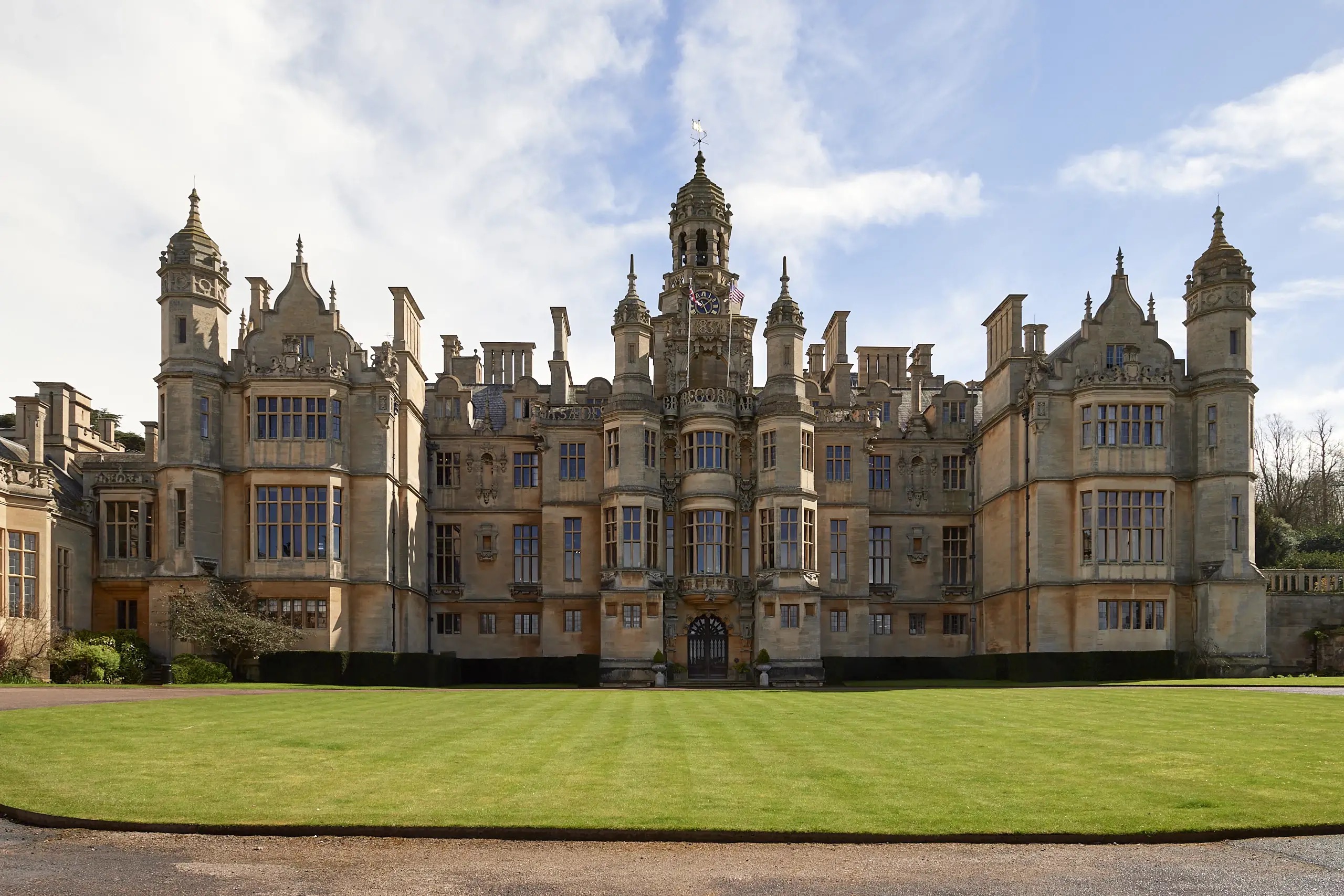 The full entrance front with its central clock tower and turrets, across the forecourt lawn, Harlaxton Manor