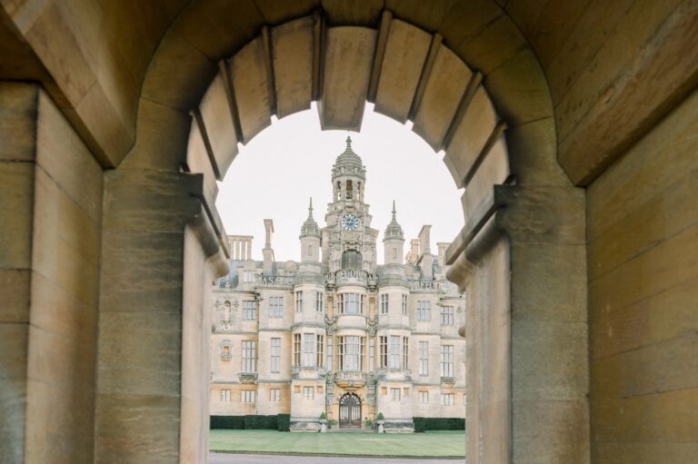 The entrance front framed by a stone archway in the forecourt walls, Harlaxton Manor