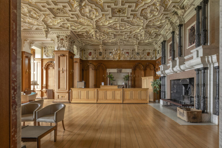 The State Dining Room bar, with an ornate plaster ceiling, oak panelling and a black marble fireplace, Harlaxton Manor