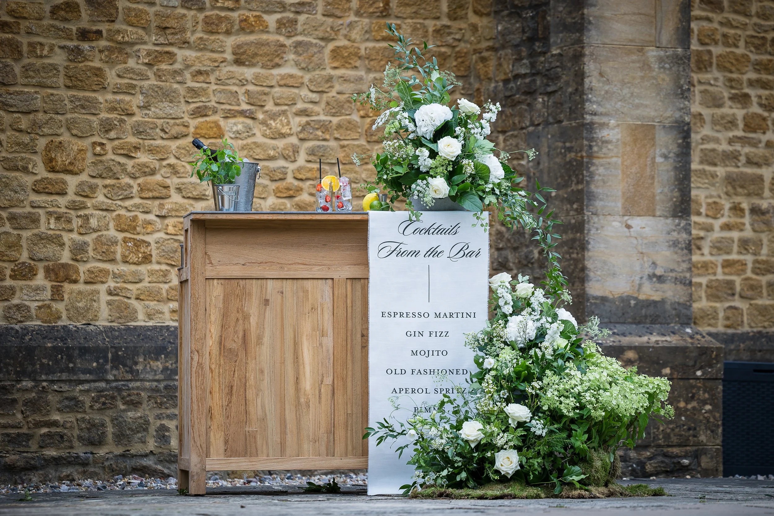 A cocktail bar, dressed with garden flowers against hamstone, Haselbury Mill