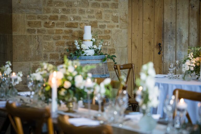 A wedding cake and candlelit table in the barn, Haselbury Mill