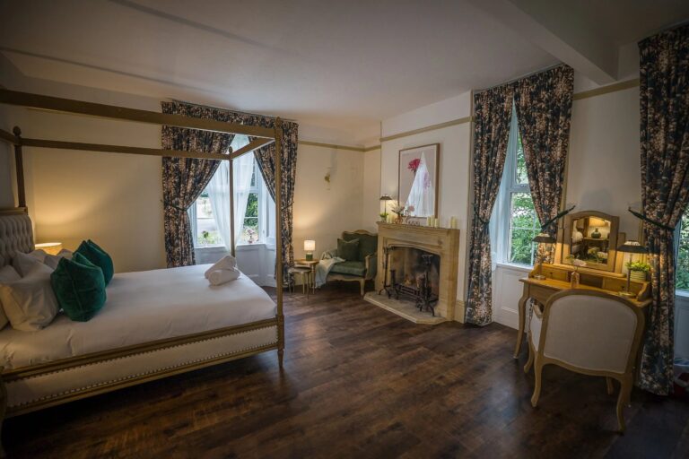 A guest room with a fireplace and floral curtains, Haselbury Mill