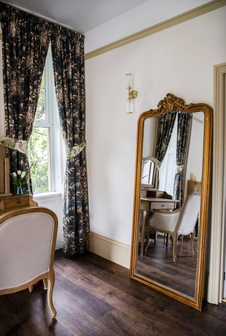 A guest room with a gilt mirror and floral curtains, Haselbury Mill