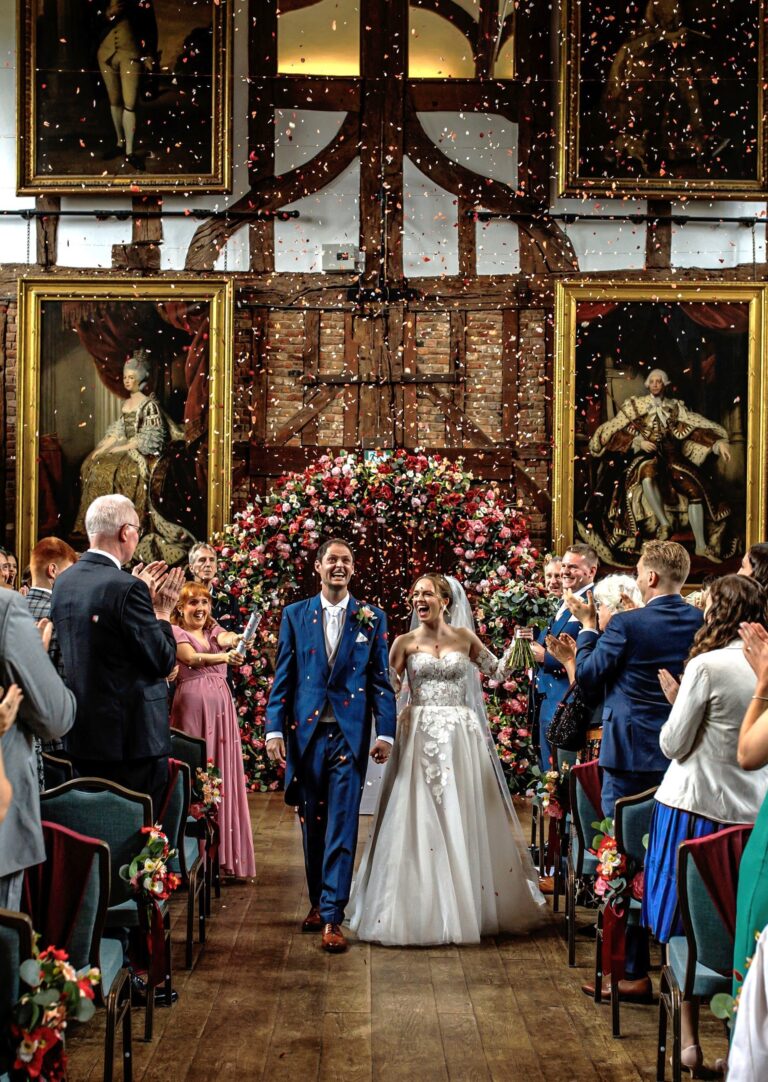 A couple walking down the aisle in the Old Palace, Hatfield House