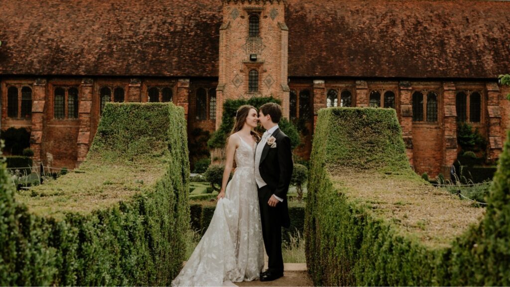A couple between clipped hedges beside the Old Palace, Hatfield House