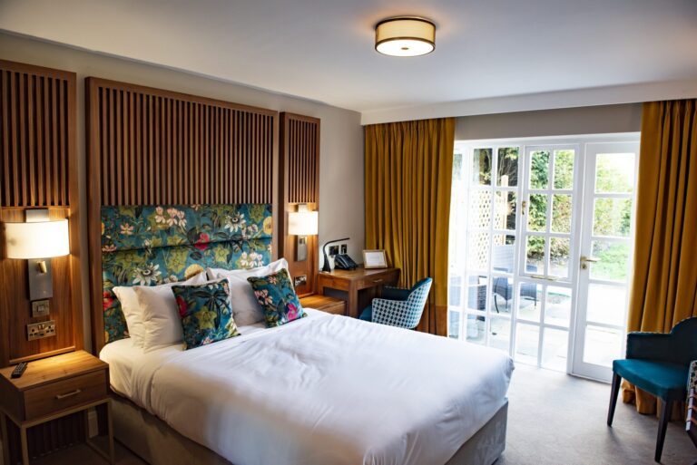 A garden room with patterned headboard and doors onto a private patio, Haycock Manor
