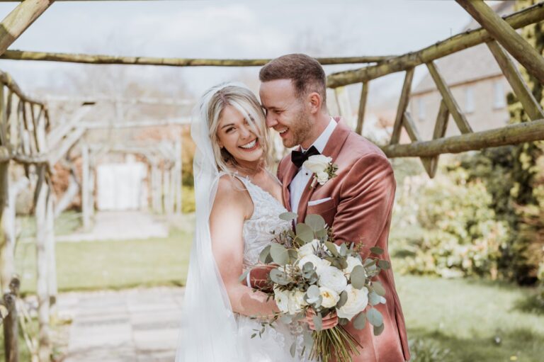 A couple under a rustic wooden pergola in the hotel garden, Haycock Manor