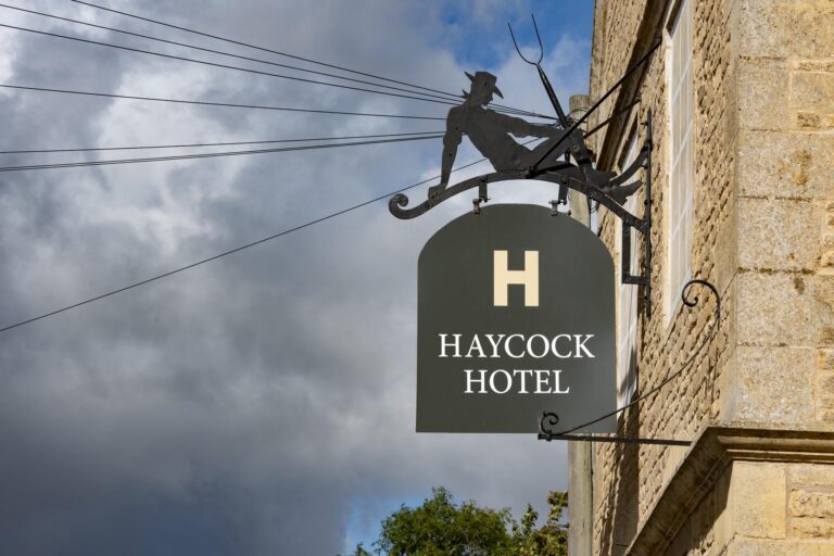 The hanging Haycock Hotel sign and fox weathervane bracket on the stone front, Haycock Manor
