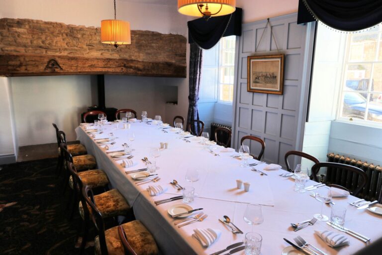 The Fitzwilliam, a panelled room with a long table laid for private dining beside windows onto the village, Haycock Manor
