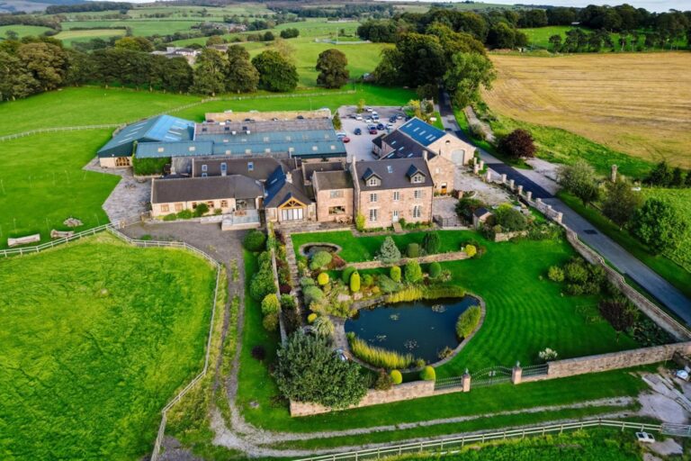 Aerial view of the farm buildings, the walled water gardens with their pond and the surrounding fields, Heaton House Farm