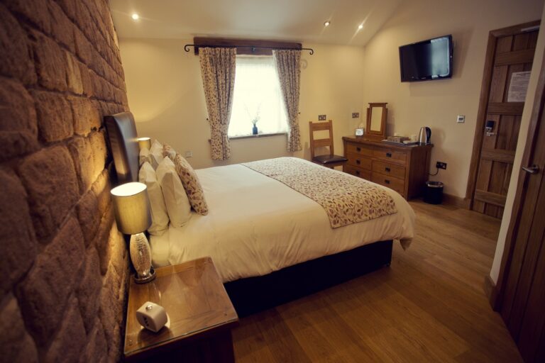 A double room with a bare stone wall and oak furniture in the converted farm buildings, Heaton House Farm