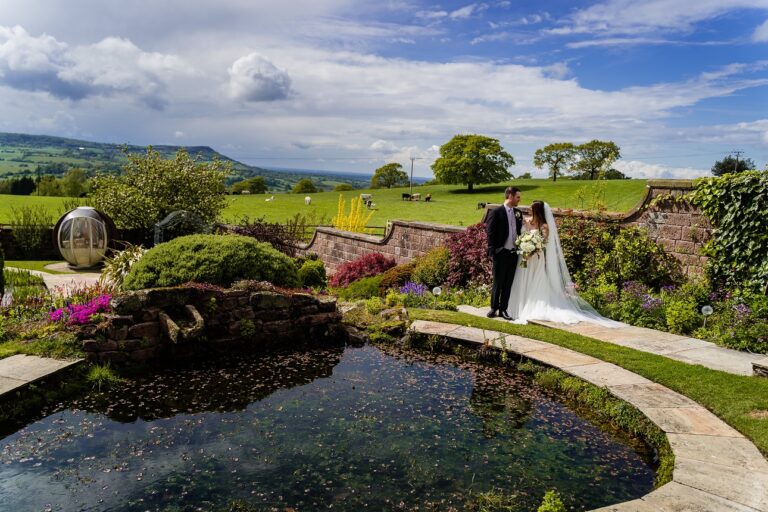 Couple beside the lily pond in the private water gardens, with the hills beyond, Heaton House Farm