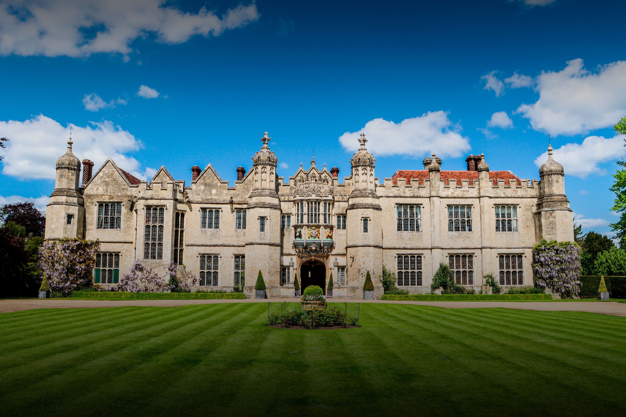 The mullioned Tudor facade of Hengrave Hall across a striped lawn under a blue sky, Hengrave Hall