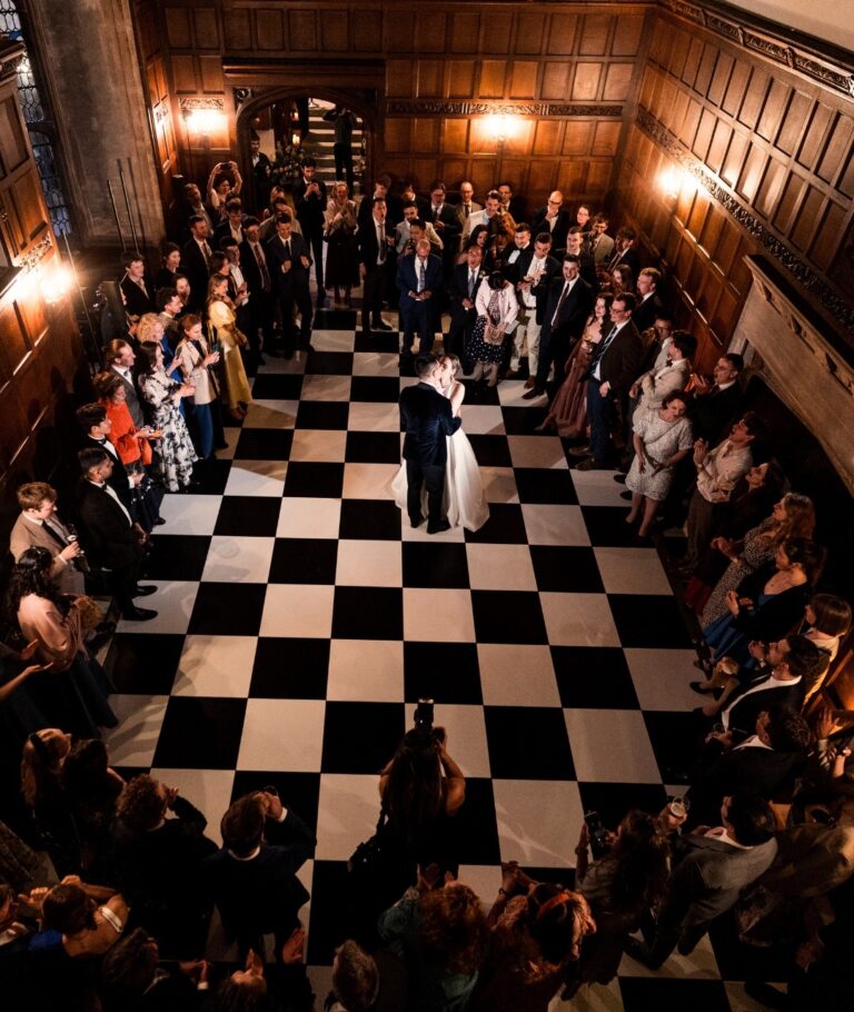 Guests dancing on a black-and-white chequered floor in the panelled hall at night, Hengrave Hall