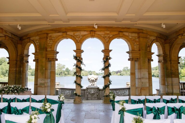 The Loggia in the Italian Garden dressed for a ceremony, stone columns and chairs with green sashes above the lake, Hever Castle