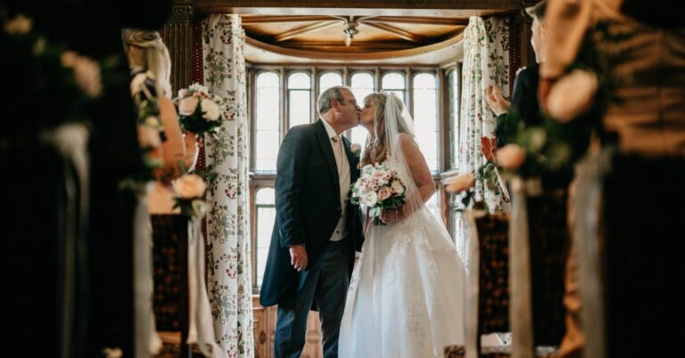 A couple kissing in a bay window framed by a floral archway in the Tudor Suite, Hever Castle