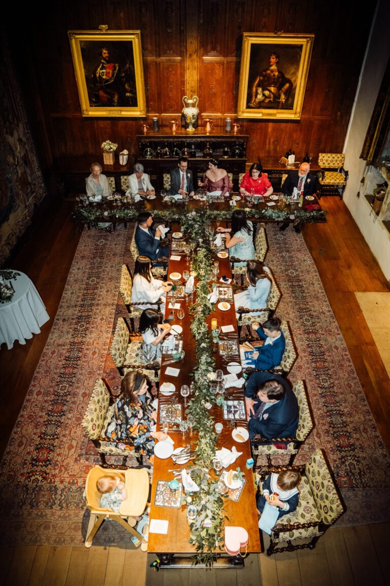 A long banqueting table set with a greenery runner beneath portraits in the castle Dining Hall, Hever Castle