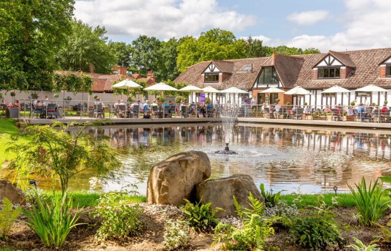 Tables and parasols on the lakeside restaurant terrace beside the water, Hever Castle