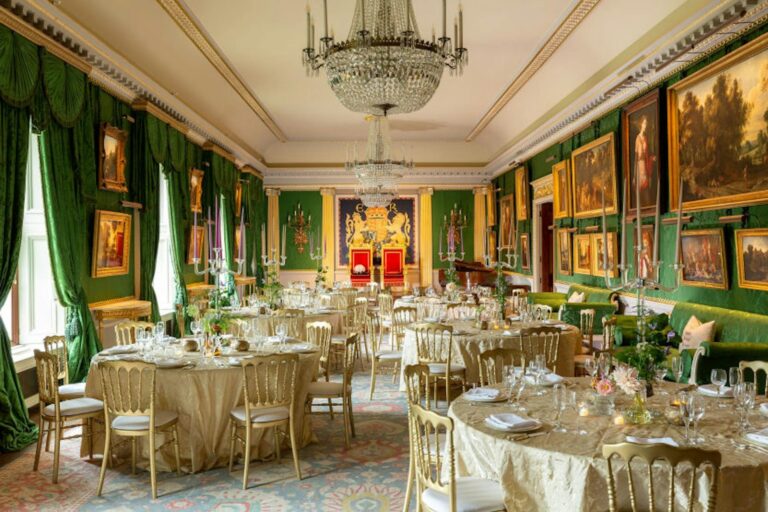 Round tables dressed with gold linen in the green State Drawing Room, Hillsborough Castle and Gardens