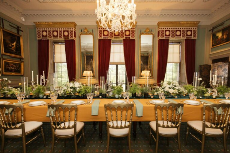 A long banqueting table in the State Dining Room, gold linen against crimson walls, Hillsborough Castle and Gardens