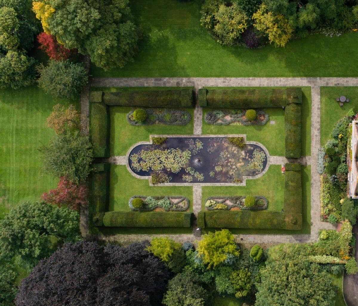 The walled lily pond garden from directly above, with clipped hedges and the oval pond at its centre, Horwood House Hotel & Spa