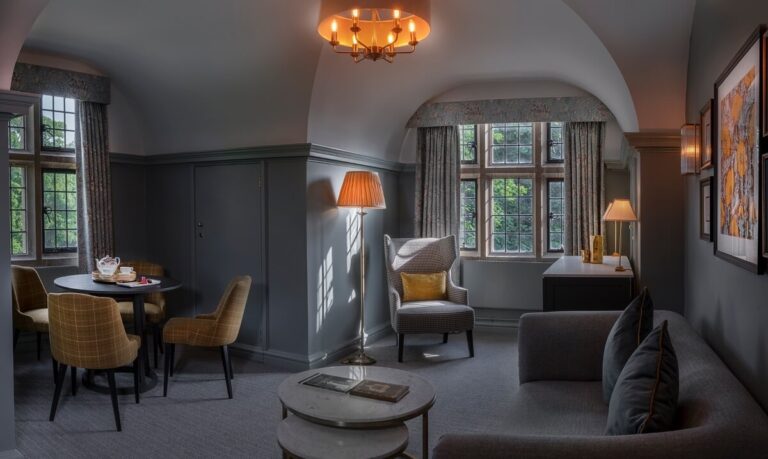 A Manor Suite sitting room under a vaulted ceiling, with sofa, armchair and a small dining table, Horwood House Hotel & Spa