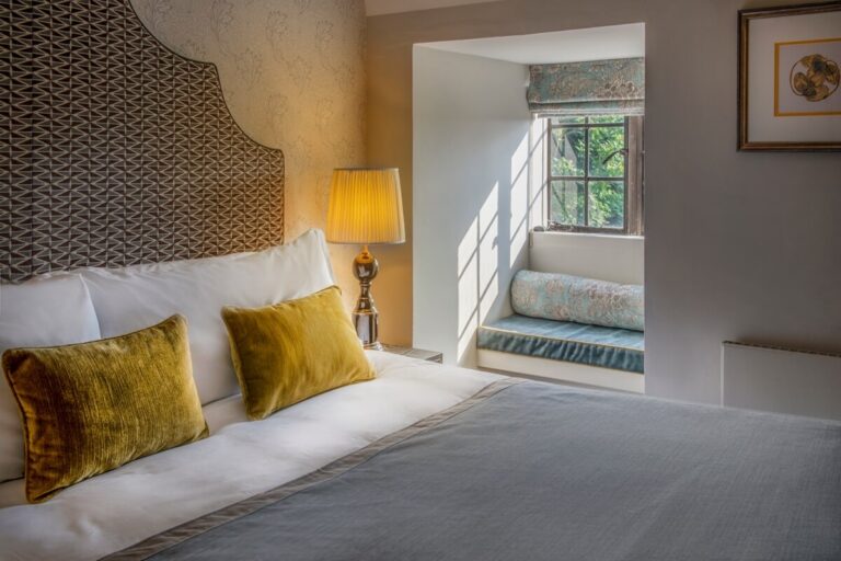 A Manor Suite bed with velvet cushions and a window seat set into the wall, Horwood House Hotel & Spa