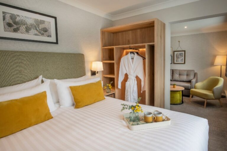 An Executive Suite bedroom with a king-size bed and a lounge area beyond, Horwood House Hotel & Spa