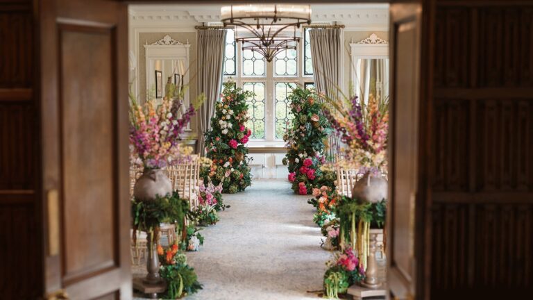 A ceremony aisle lined with flowers, seen through open panelled doors, Horwood House Hotel & Spa