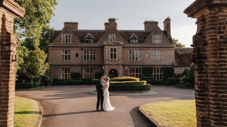 A couple on the forecourt seen through the brick gate piers, with the Manor House entrance front behind, Horwood House Hotel & Spa