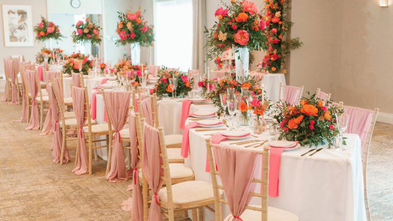 Long tables with pink sashes and bright floral centrepieces laid for a wedding breakfast, Horwood House Hotel & Spa