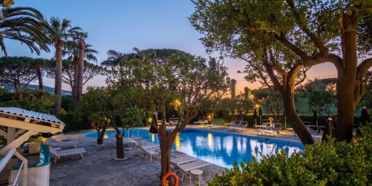 The pool and gardens at dusk, palm trees at the water's edge, Hotel Alpha
