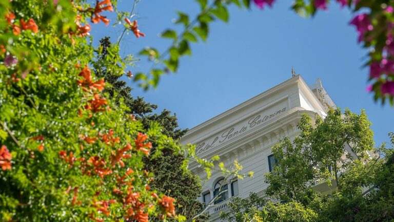 The hotel building framed by flowering trees, Hotel Santa Caterina