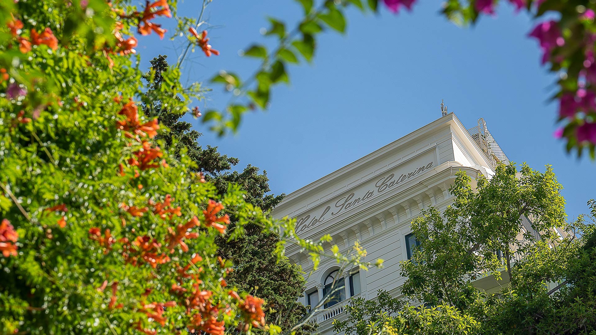 The hotel building framed by flowering trees, Hotel Santa Caterina