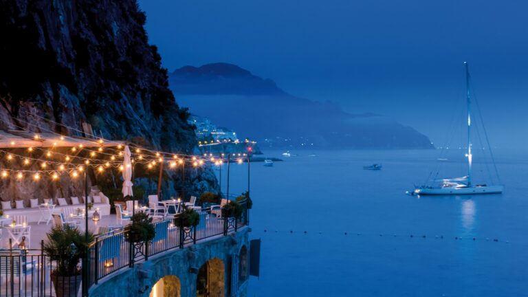 The Grottino terrace lit at dusk above the sea, Hotel Santa Caterina