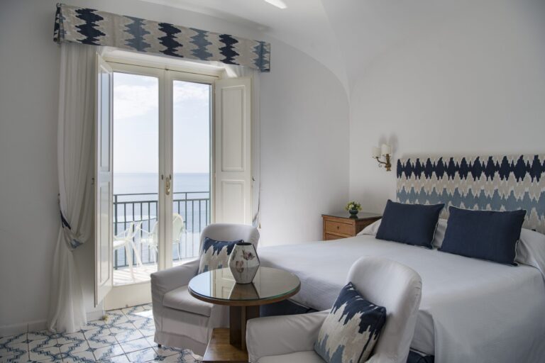 A room with a blue headboard and balcony doors, Hotel Santa Caterina