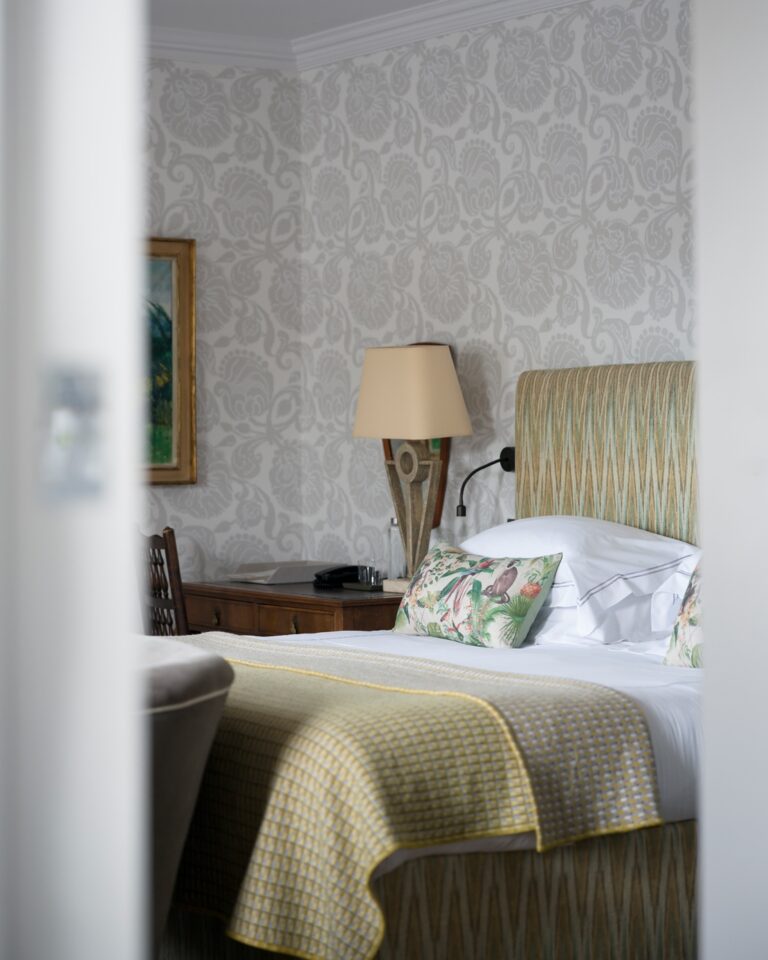 A bedroom with a yellow throw and patterned walls, Hotel Tresanton