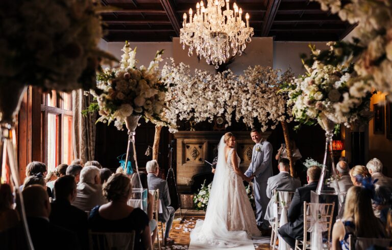 A ceremony in the Great Hall beneath a chandelier, Huntsham Court