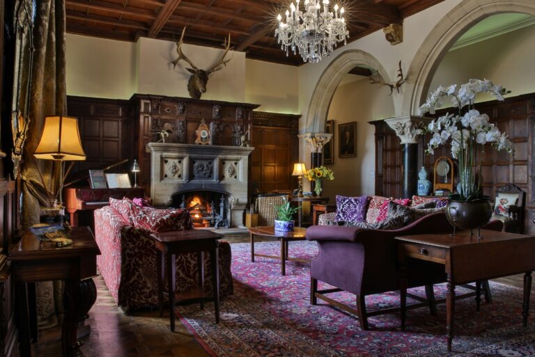 A panelled room with a fire and deep sofas, Huntsham Court